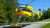 Yellow adac luftrettung rescue helicopter landing in front of blue sky and trees.