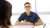 Young man sitting at a desk wearing glasses and a blue shirt