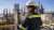 Young woman engineer looking out over plant wearing protective gear