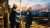 Two workers in hard hats overlook Rotterdam refinery at sunset
