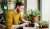 man on laptop sitting by desk with plants