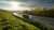 White truck driving on the highway turning towards the horizon in an autumn landscape with sun shining through the clouds in the sky