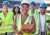 A group of five workers stand in a group wearing hard hats and yellow vests